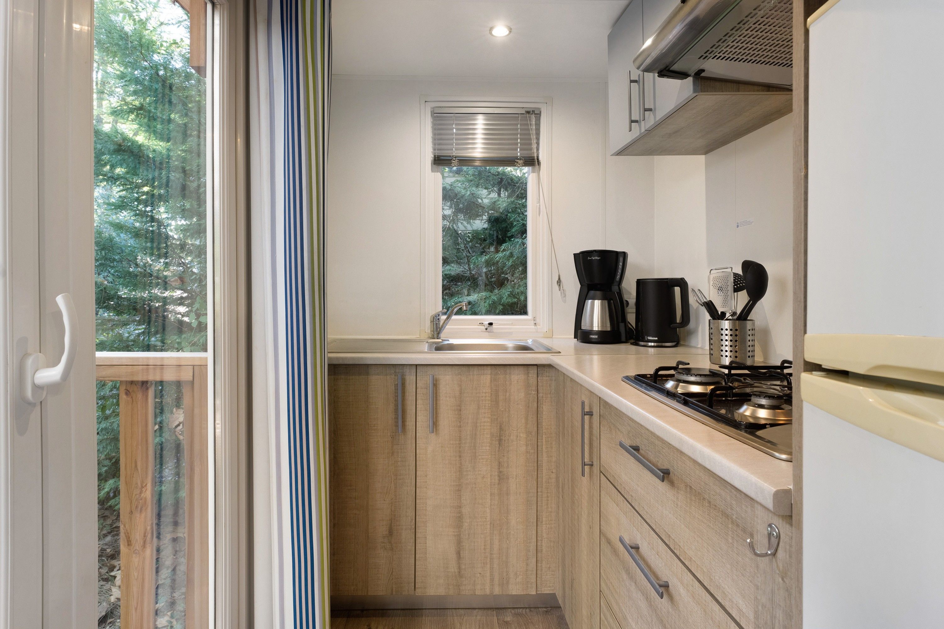 Una cocina compacta con ventana, cafetera y estufa.