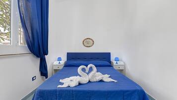 Ein Einzelbett mit blauer Bettdecke und zwei weißen Handtüchern, die zu einem Herz geformt sind.