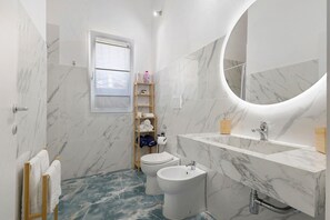Une salle de bain comprenant des toilettes, un bidet et un lavabo avec un miroir.