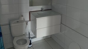 A bathroom with a toilet, sink, and mirror. - Vrbo Property (La Trinité)
