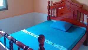 A room with a wooden bed, a blue bedspread, and a window. - Vrbo Property (La Trinité)