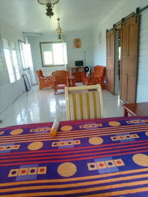 A room with a bed, a TV, and a wooden door. - 🌴 Your little corner of paradise on the Caravelle Peninsula (La Trinité)