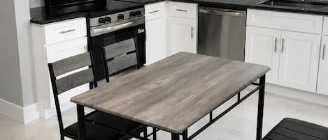 A modern kitchen with white cabinets, a stainless steel oven, a microwave, and a dishwasher.