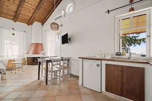 A kitchen with a tiled floor, wooden cabinets, a built-in oven, and a window with a view of trees. - Holiday Home 'Villa Meltemi' with Sea View, Wi-Fi, and Air Conditioning (Tsoukalades)