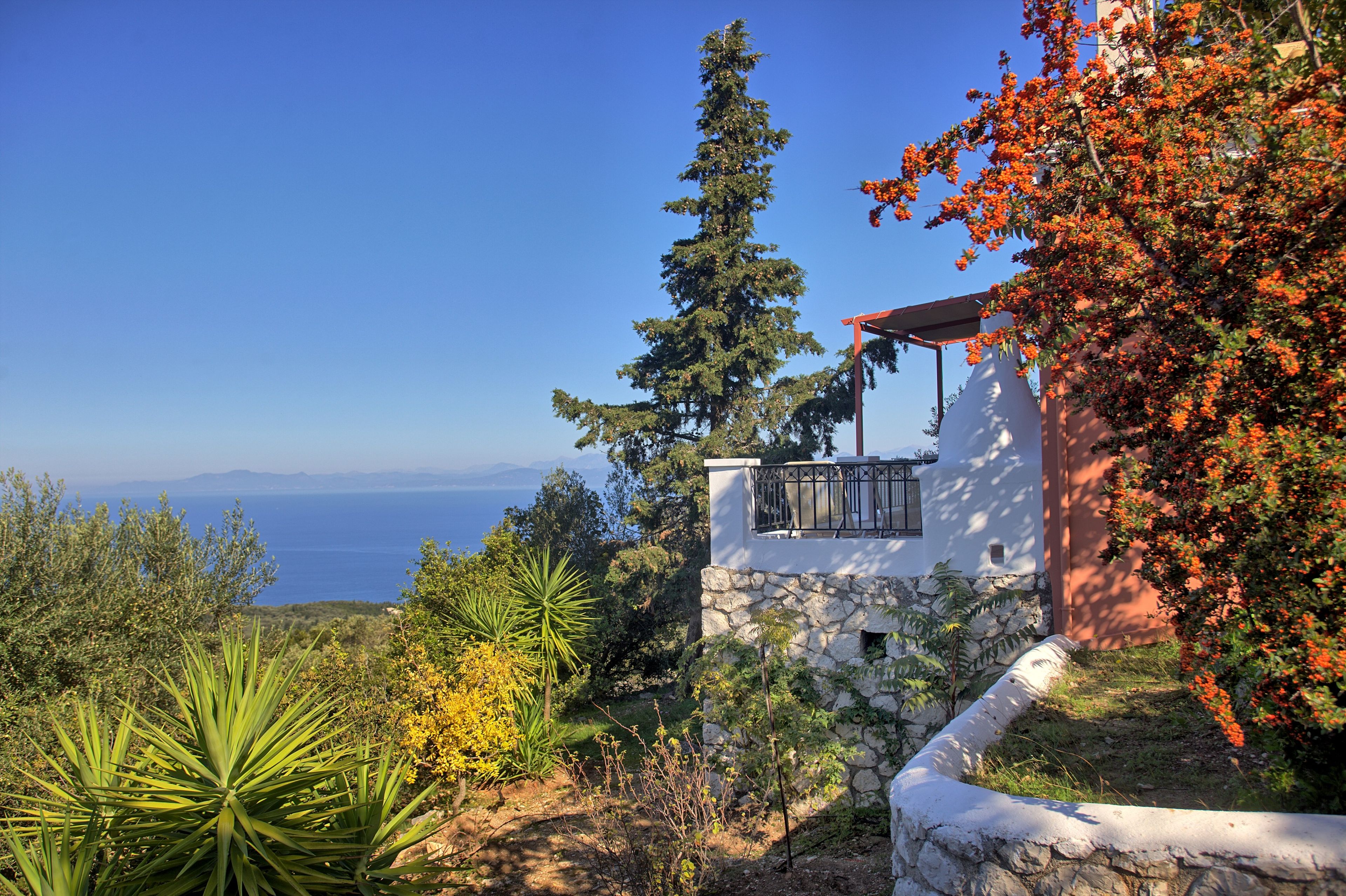 A coastal property with a stone wall, a balcony, and a view of the sea.