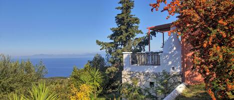 A coastal property with a stone wall, a balcony, and a view of the sea.