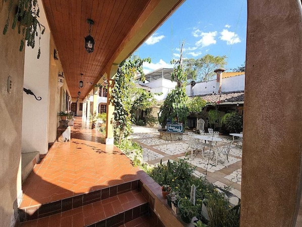 Un espace extérieur abrité, doté d’un sol carrelé, de plantes en pot et de mobilier d’extérieur.
