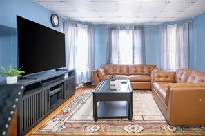 Un salon doté d’un grand téléviseur à écran plat, de canapés en cuir, d’une table basse et de tapis à motifs.