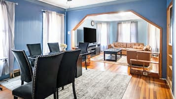 Una sala de estar con televisor, sofá y sillones.