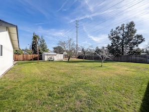 A backyard with a wooden fence, a shed, and a tall utility pole.