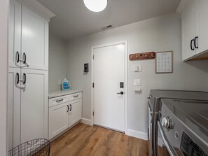A kitchen with white cabinets, a stainless steel stove, and a wooden floor.