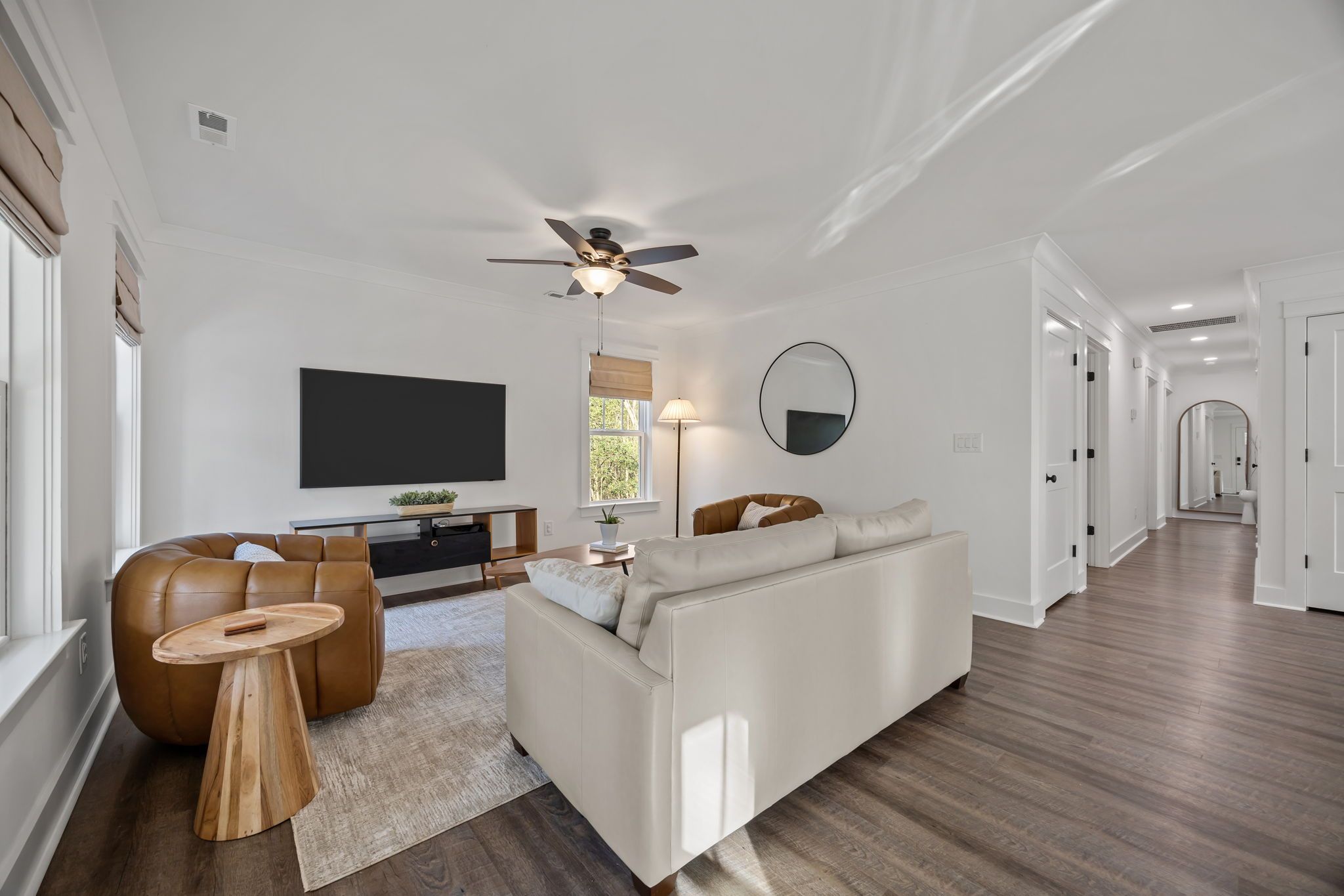 A modern living room with a sofa, a coffee table, a TV, and a ceiling fan.