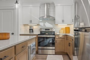 Una cocina moderna con electrodomésticos de acero inoxidable, armarios de madera y horno empotrado.