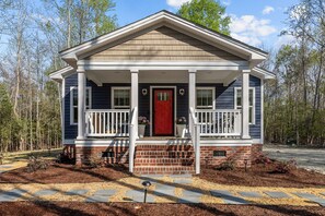 A two-story house with a red front door, white railings, and a brick foundation. - The Villanore Scandinavian-Inspired Corporate Retreat (Greenville)