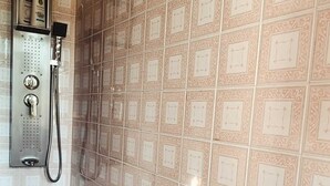 A bathroom with patterned tiles, a shower, and a hand dryer.
