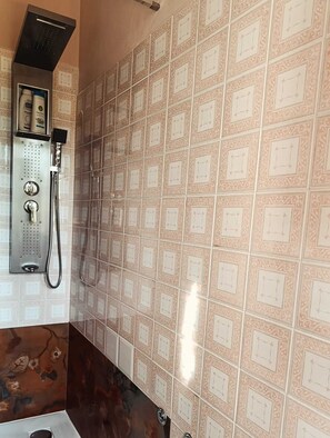 A bathroom with patterned tiles, a shower, and a hand dryer.