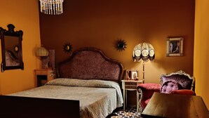 Quarto com cama, mesa de cabeceira, cômoda, espelho, lustre e piso estampado.