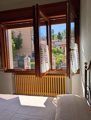 Una stanza con un letto, un termosifone e una finestra con tende.