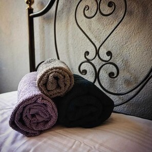 A bed with rolled towels in various colors.