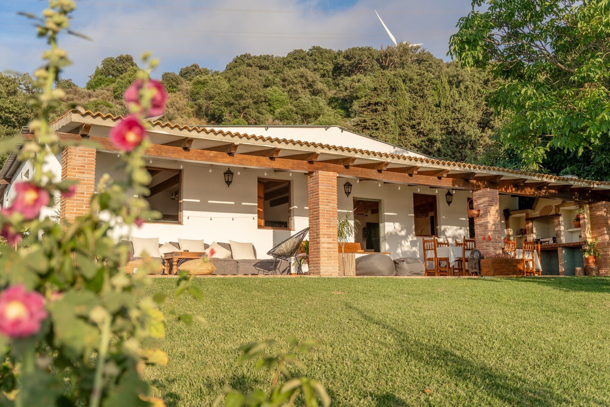 Una casa con un patio, una chimenea de ladrillo y vistas al bosque circundante.