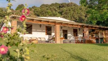 Una casa con un patio, una chimenea de ladrillo y vistas al bosque circundante.