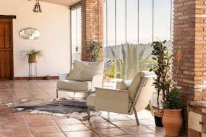 A spacious patio with two leather sofas, a rustic rug, and potted plants.