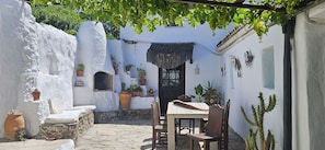 A courtyard with a table and chairs, surrounded by white walls and potted plants. - Private Andalusian Villa with Pool and Views in Casares (Casares)