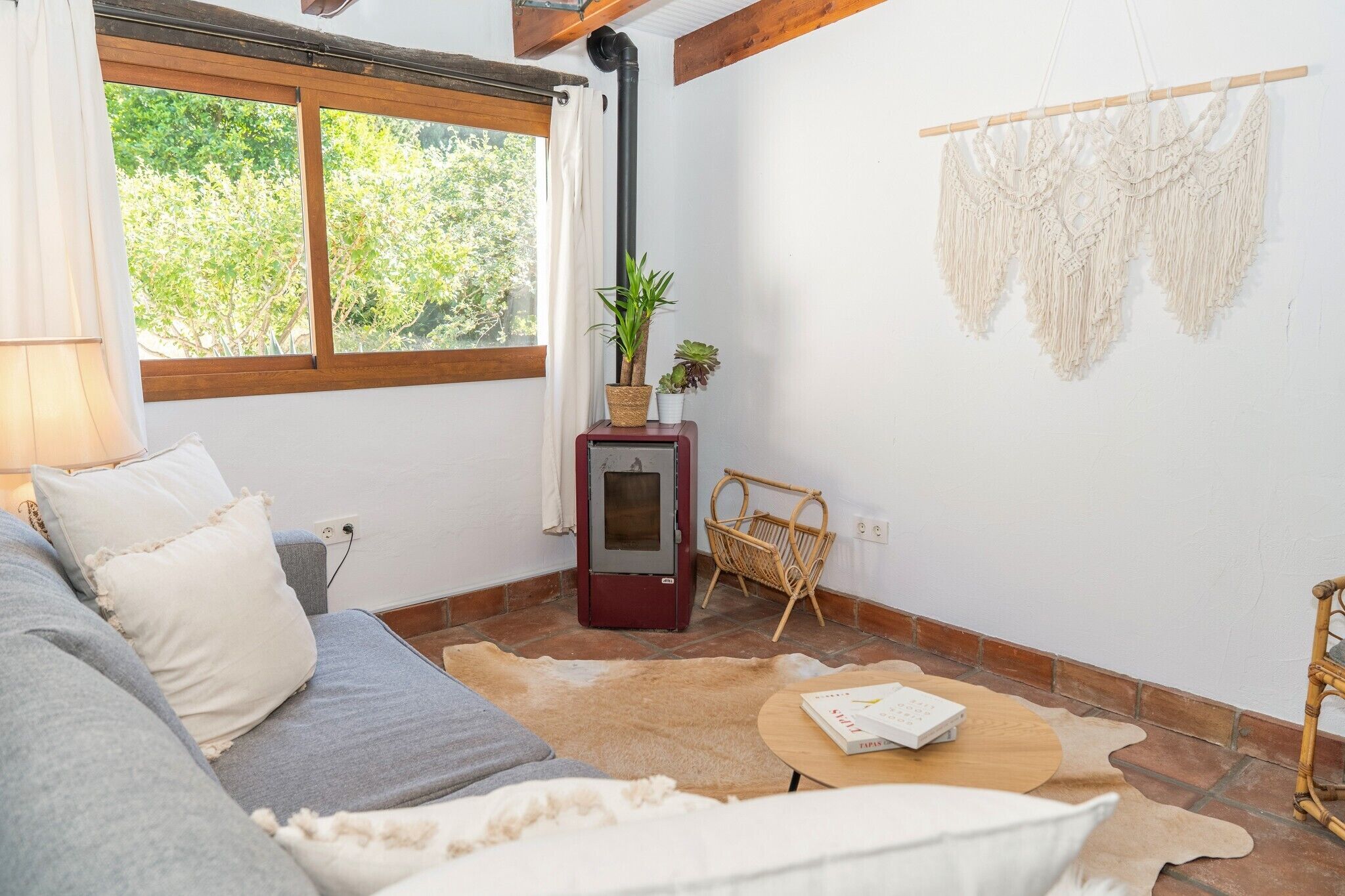 Una habitación acogedora con sofá, una mesita, calefacción y una ventana con cortinas.