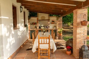 An outdoor patio with a dining table set for four, surrounded by wooden chairs.