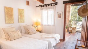 Een kamer met twee bedden, een lamp, een raam met gordijnen en uitzicht op het omliggende landschap.