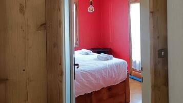 Una habitación con una cama, una lámpara colgante y una pared roja.