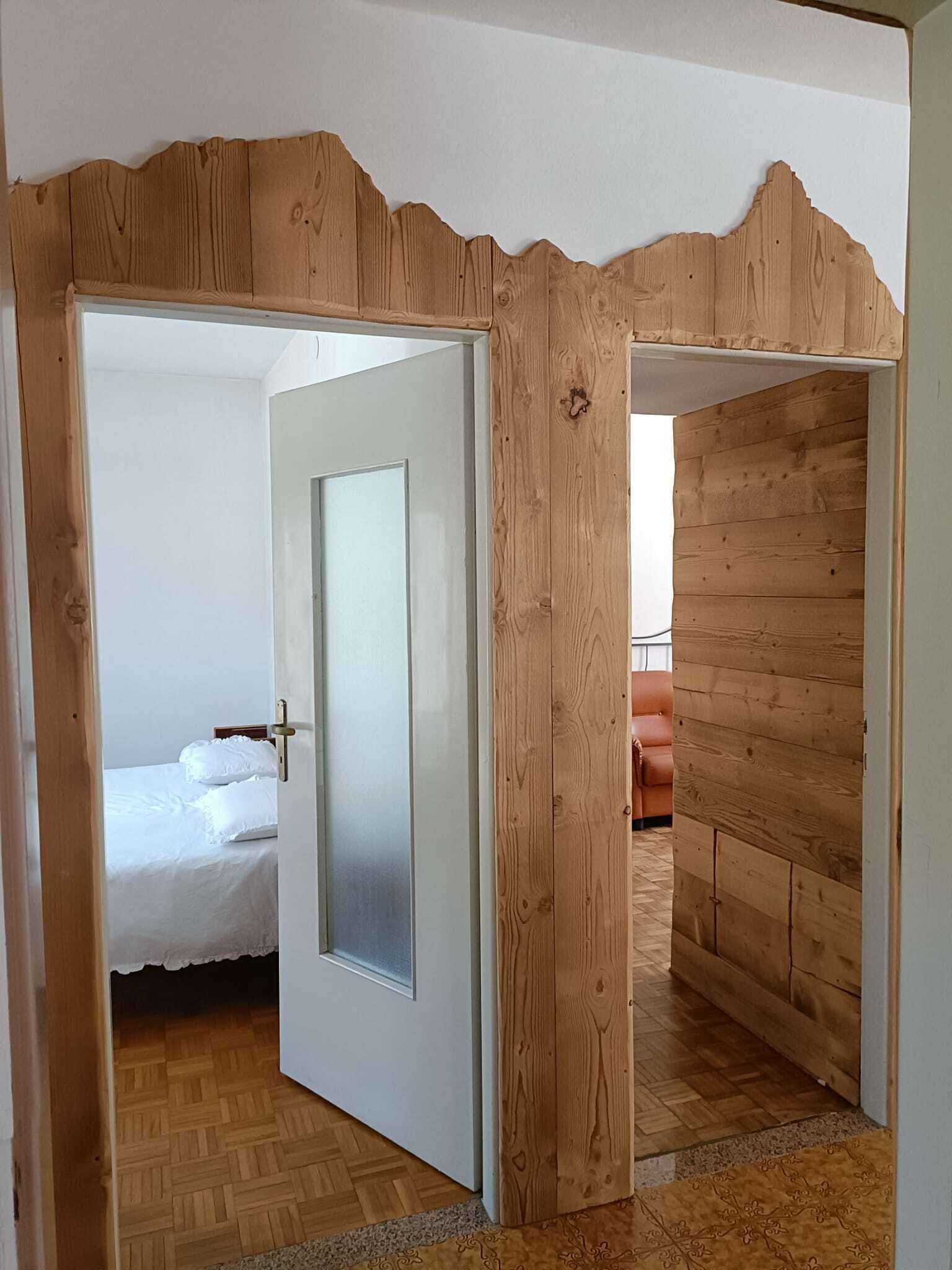 Una habitación con cama, puerta y paredes de madera.