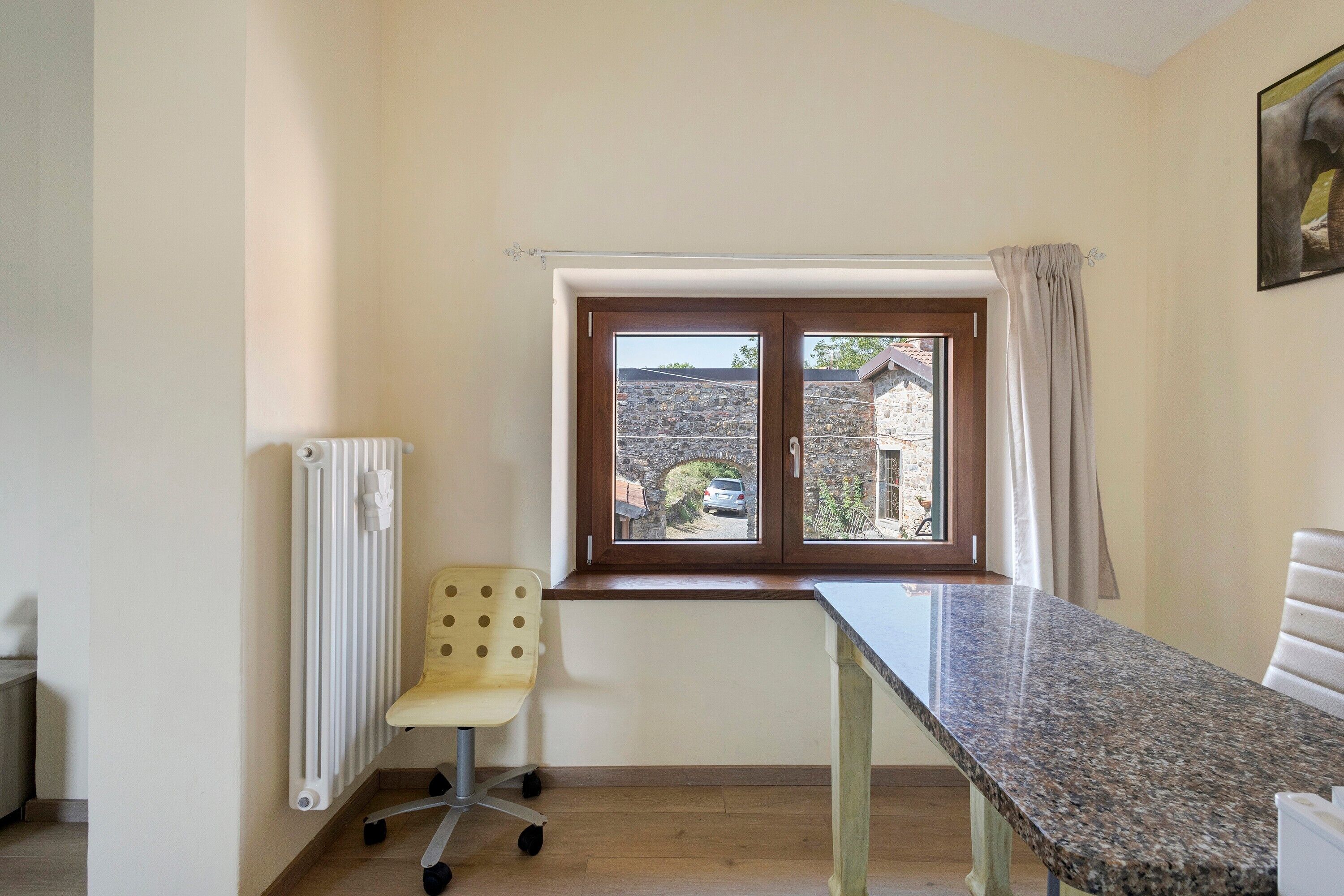 Une pièce avec une fenêtre, un radiateur, une chaise et une table.