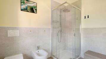 Ein Badezimmer mit Duschkabine, Bidet und Toilette.