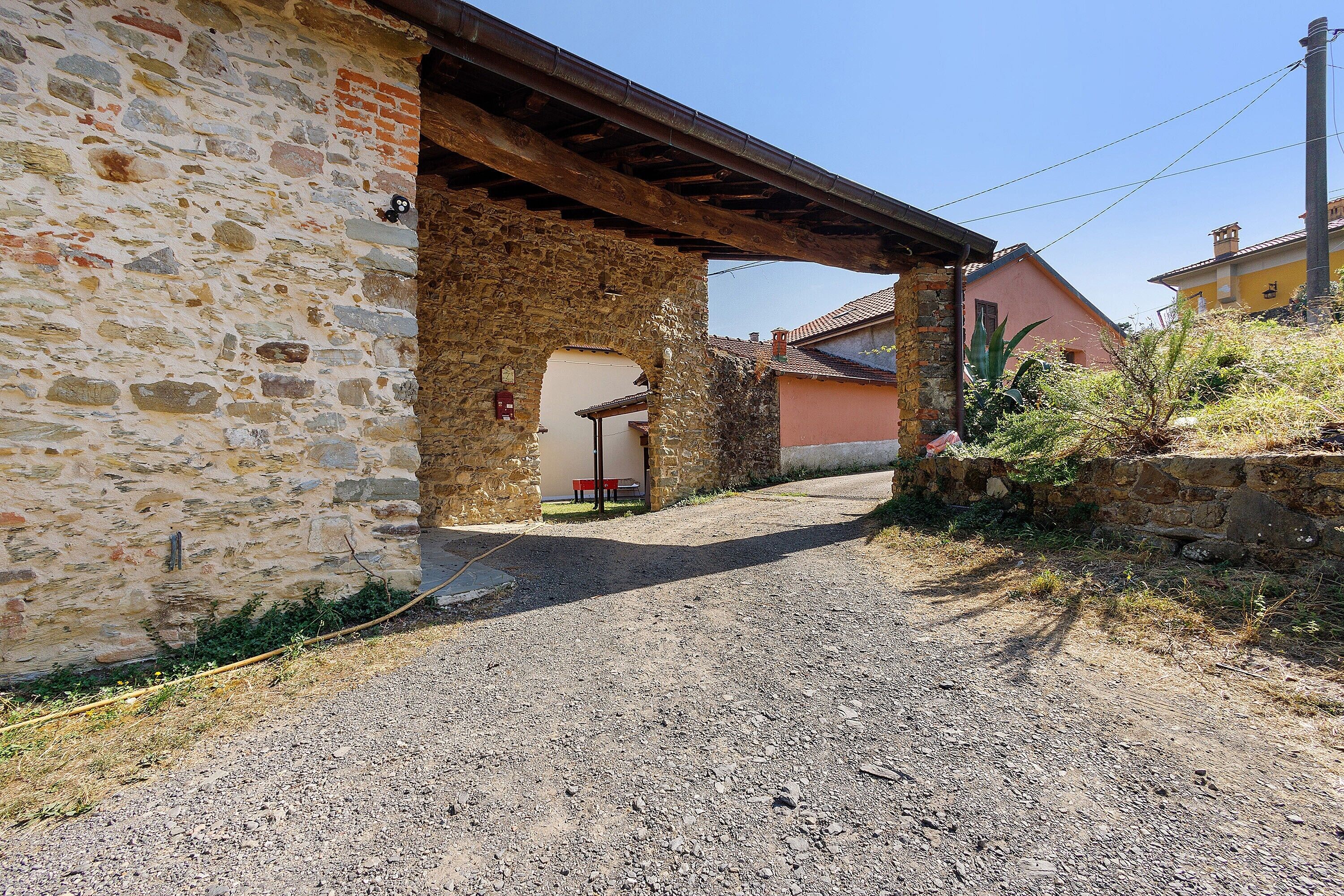 Un camino de grava que conduce a un edificio de piedra con un alero de madera.