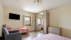 Quarto com cama, cadeira, televisão e janela com vista.