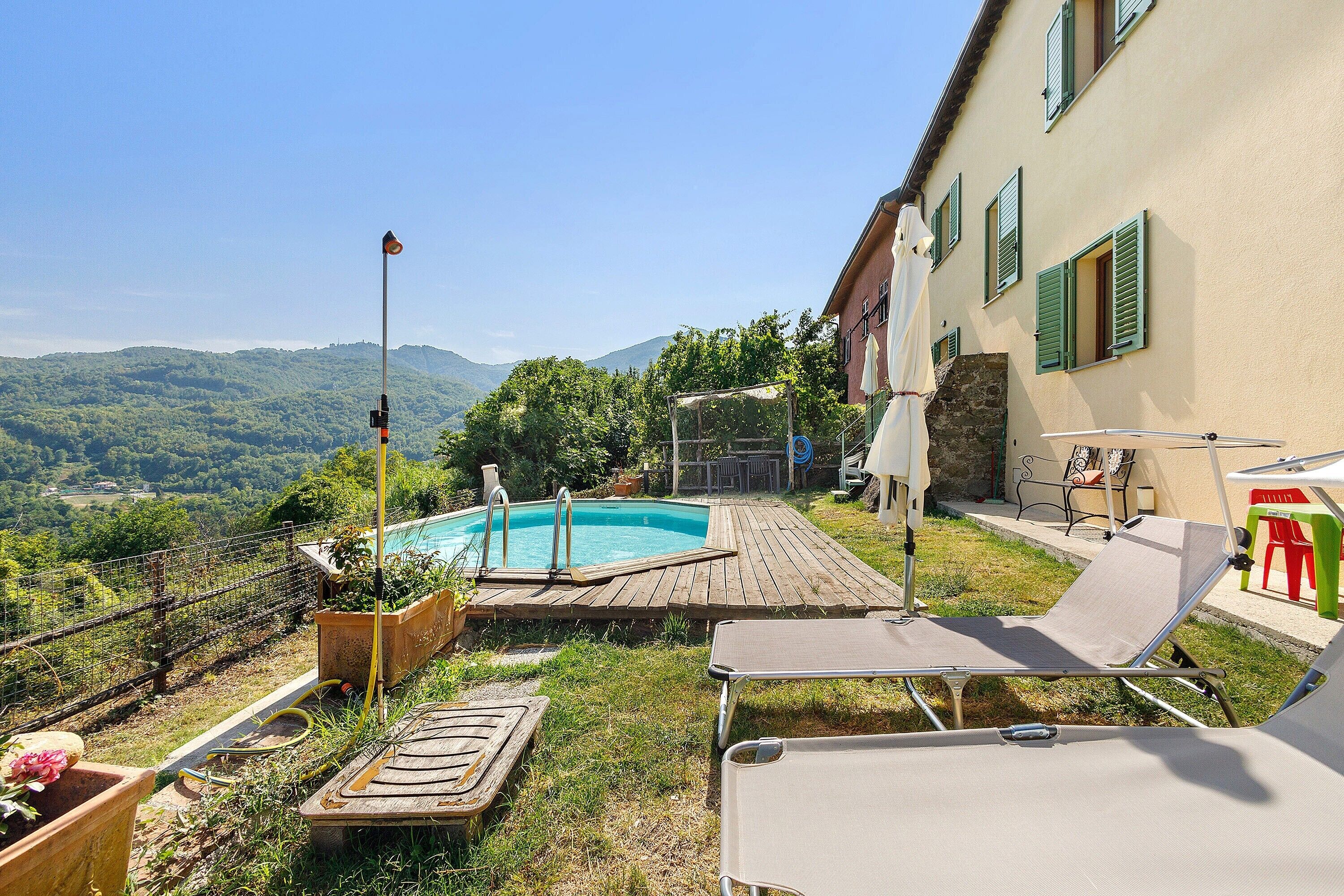 Un espace piscine doté d’une terrasse en bois, de chaises longues et offrant une vue sur les montagnes.