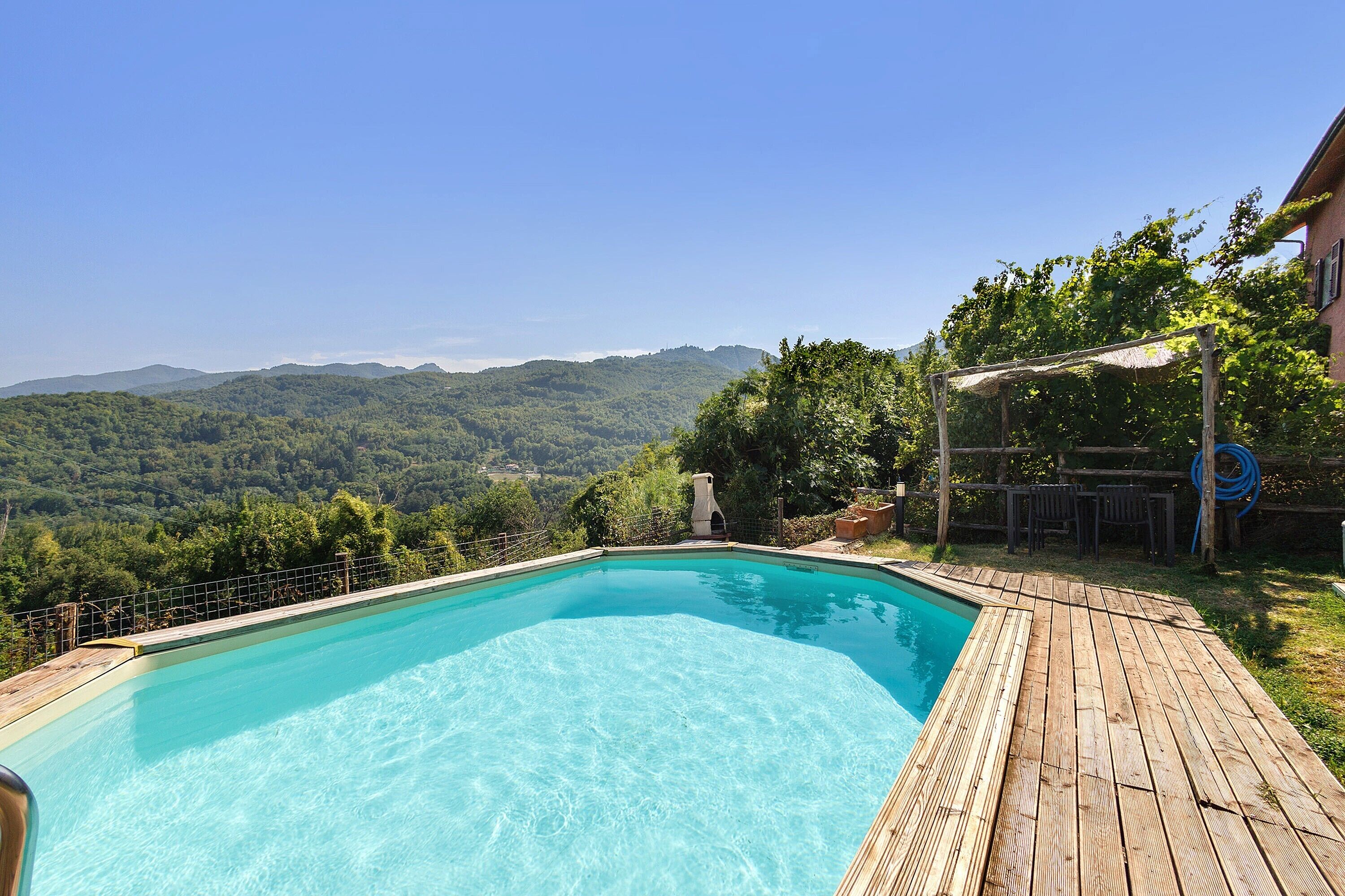 Una piscina rectangular con muelle de madera que la rodea, con un paisaje montañoso de fondo.