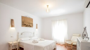 A bedroom with a bed, bedside tables, a desk, a chair, and a window with curtains.
