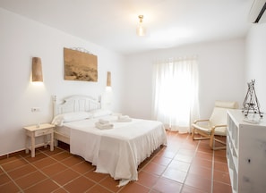 A bedroom with a bed, bedside tables, a desk, a chair, and a window with curtains.