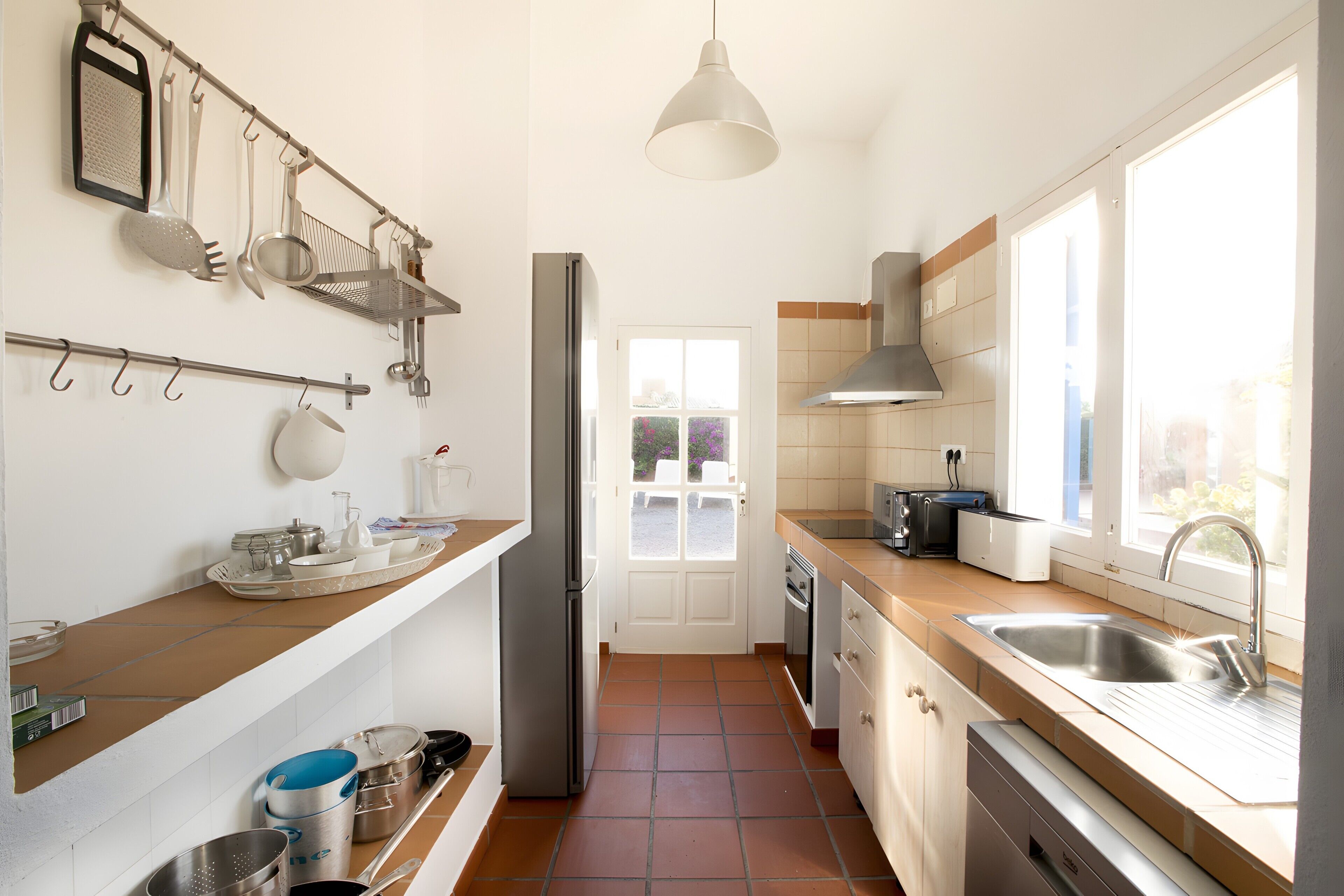A modern kitchen with a refrigerator, stove, sink, and various utensils.