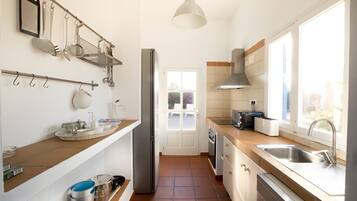 A modern kitchen with a refrigerator, stove, sink, and various utensils.