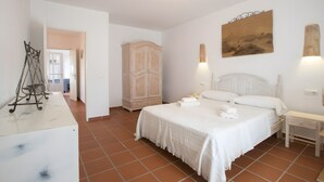 A bedroom with a bed, bedside tables, a wardrobe, and a painting on the wall. - Casa Rita in Formentera with Sea Views (Sant Ferran de ses Roques)