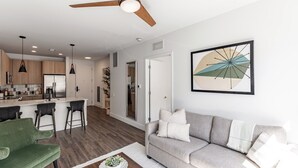Ein modernes Wohnzimmer mit einem grauen Sofa, einem grünen Sessel und einem Couchtisch mit einer Pflanze.