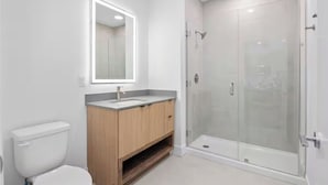 Ein modernes Badezimmer mit Toilette, Waschtisch und einer Duschkabine.
