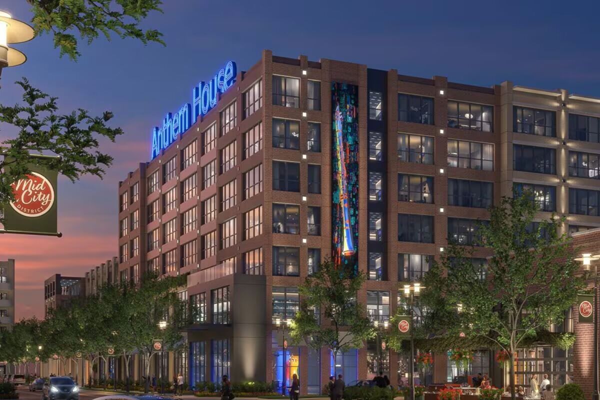 Ein Hotel mit einem gut sichtbaren Schild 'Anthem House', mehreren Stockwerken und einer großen vertikalen Anzeige an der Fassade.