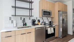 Eine moderne Küche mit Edelstahlgeräten, Holzschränken und einer gefliesten Spritzschutzwand.