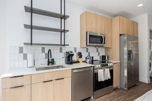 A modern kitchen with stainless steel appliances, wooden cabinets, and a tiled backsplash. - Modern Stay | 1 Unit | Central Huntsville Location (Huntsville)