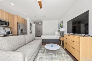 A modern hotel room with a kitchenette, a sofa, a bed, a TV, and a small table. - Modern Stay | 1 Unit | Central Huntsville Location (Huntsville)