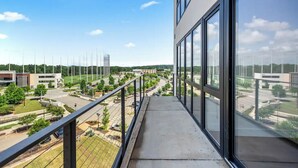 Ein Balkon mit freiem Blick auf einen Parkplatz, Gebäude und Grünflächen.